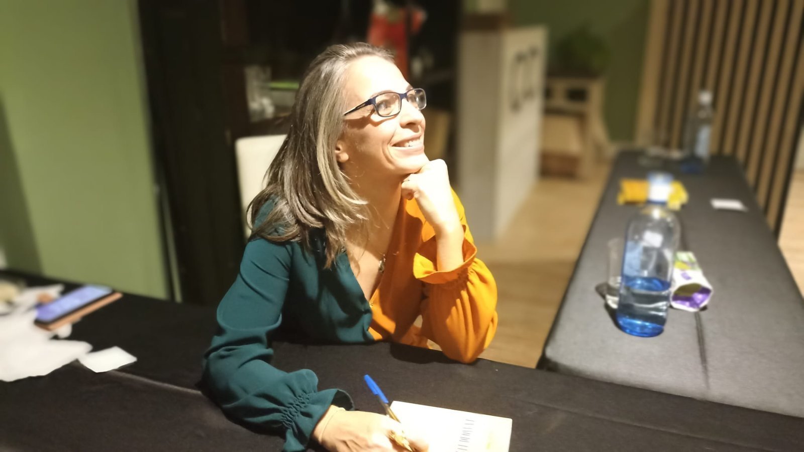 Amada Selina escribiendo pensativa y sonriente